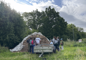 a group of people standing in a field with a pile of wood chips tình nguyện 